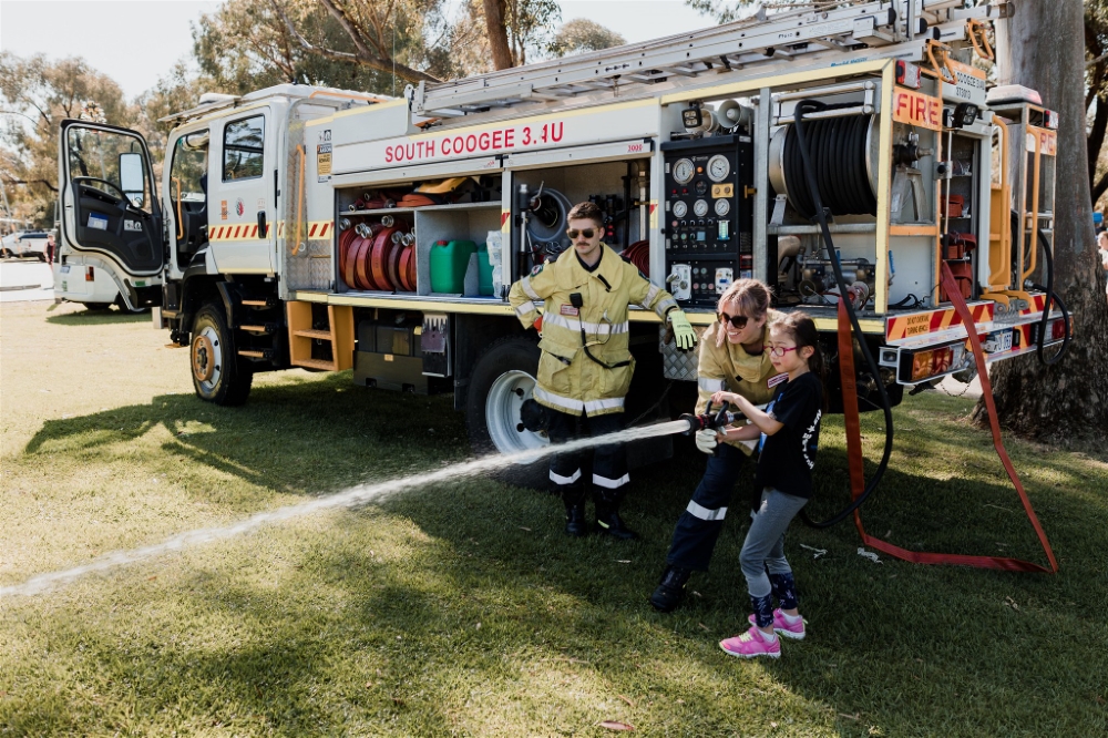 Young girl being taught to use the fire hose from a volunteer fire truck